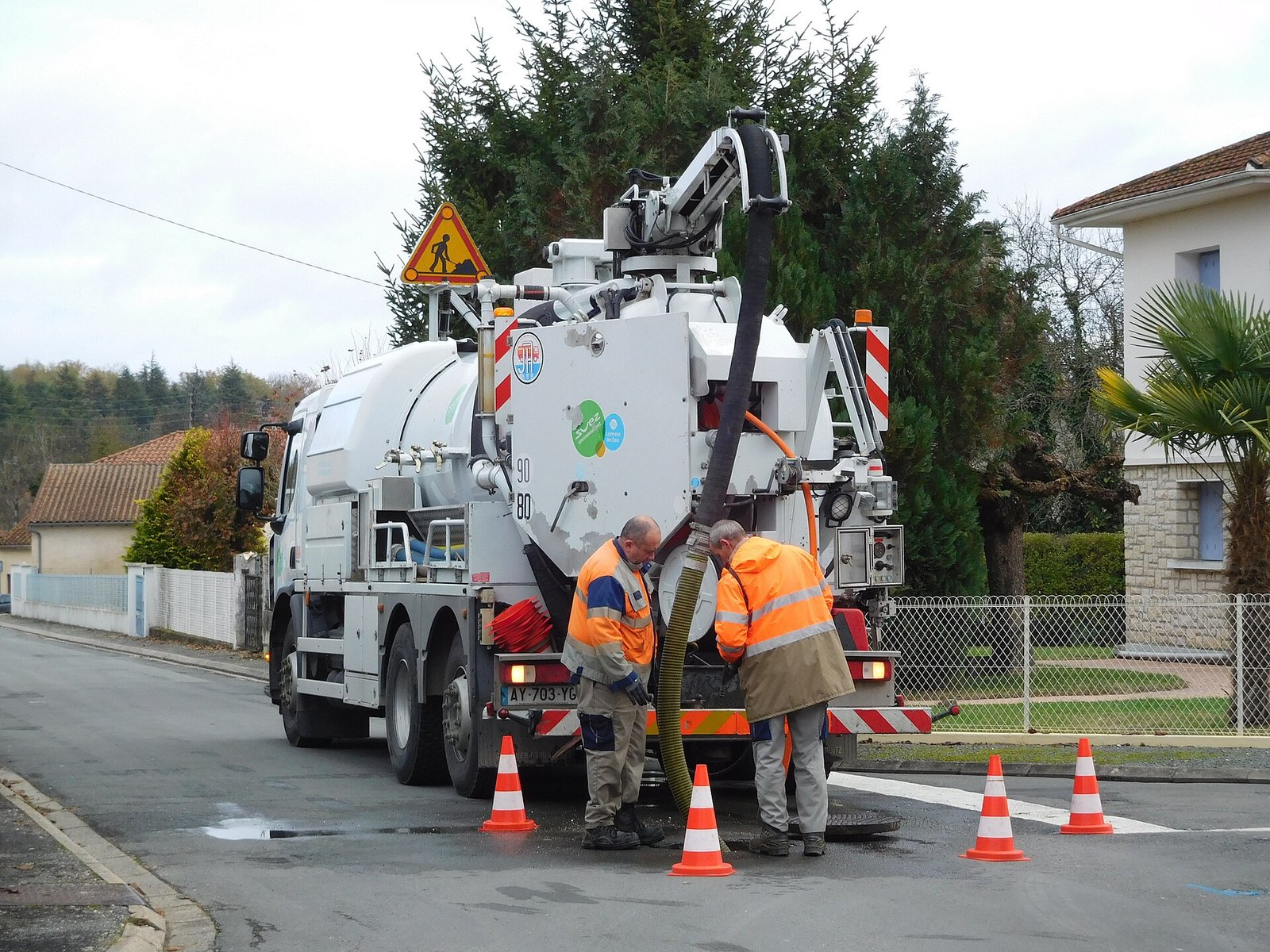 Septic vacuum truck with its hose run out to pump a tank at a home